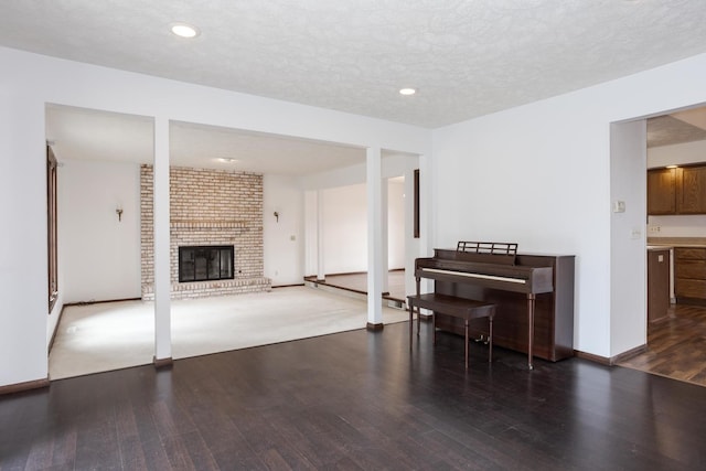 living room with a fireplace, a textured ceiling, and dark hardwood / wood-style floors