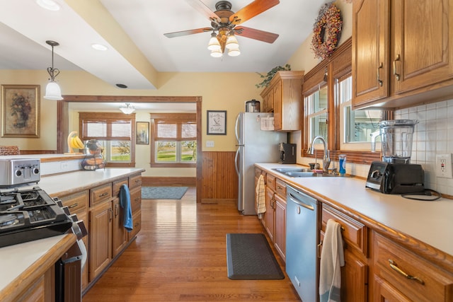 kitchen with tasteful backsplash, appliances with stainless steel finishes, light wood-type flooring, pendant lighting, and sink