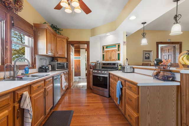 kitchen with sink, ceiling fan, stainless steel appliances, decorative light fixtures, and light hardwood / wood-style flooring