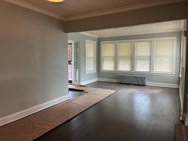 empty room featuring crown molding, a wealth of natural light, dark wood-type flooring, and radiator heating unit