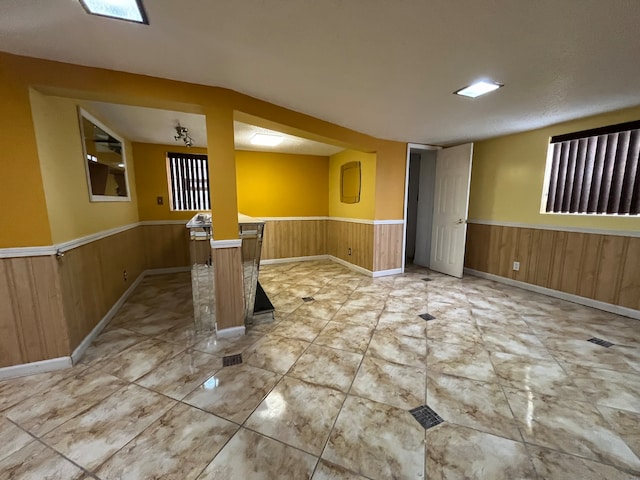 unfurnished room featuring wooden walls and a textured ceiling