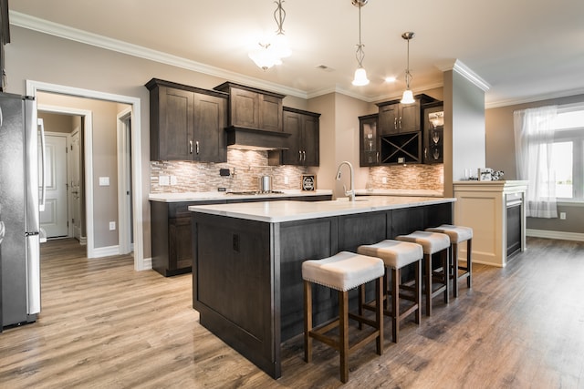 kitchen featuring stainless steel appliances, dark brown cabinetry, decorative light fixtures, and hardwood / wood-style floors