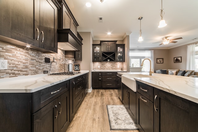 kitchen featuring appliances with stainless steel finishes, sink, light wood-type flooring, hanging light fixtures, and ornamental molding