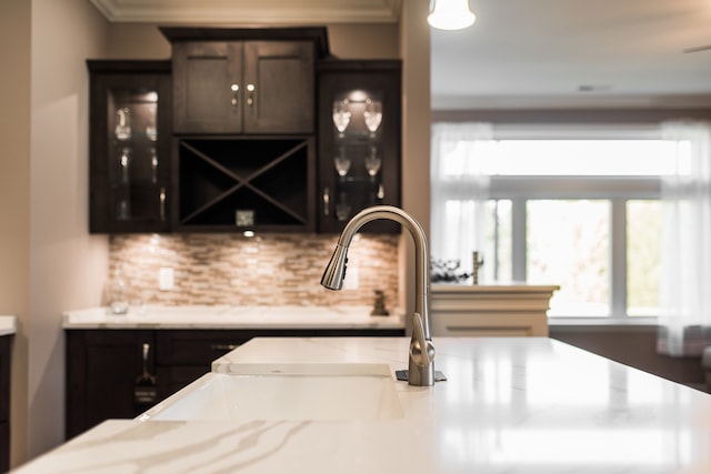 kitchen with ornamental molding, dark brown cabinetry, and sink