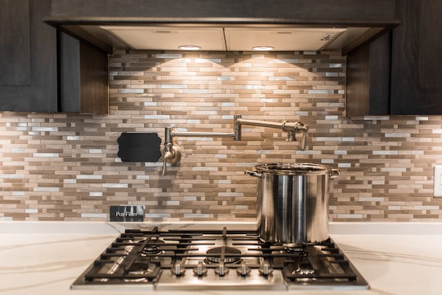 kitchen with stainless steel gas cooktop, backsplash, and dark brown cabinets