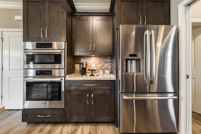 kitchen featuring stainless steel appliances, ornamental molding, and light hardwood / wood-style flooring