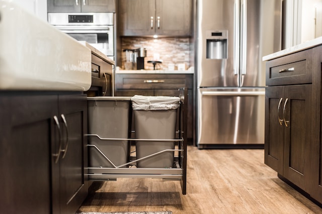 kitchen with decorative backsplash, light hardwood / wood-style flooring, dark brown cabinetry, and stainless steel appliances