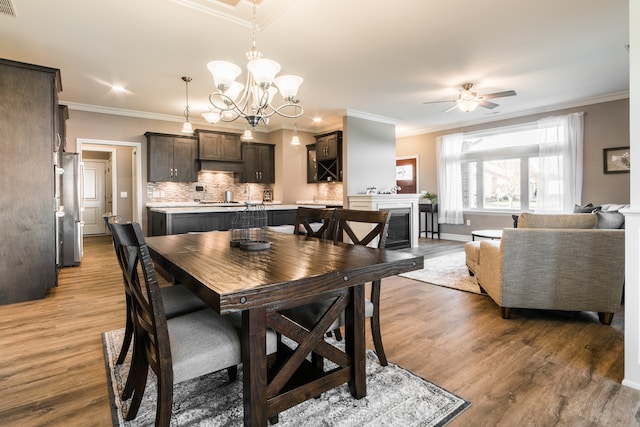 dining room featuring crown molding, light hardwood / wood-style flooring, and ceiling fan with notable chandelier