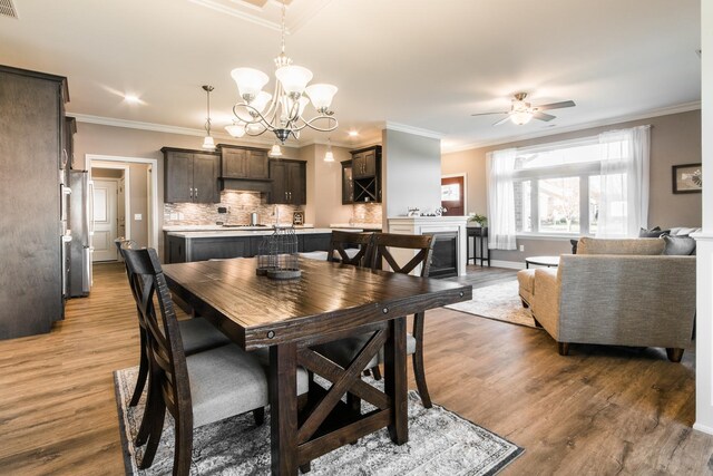 506 Stearn Dr Unit 506, Genoa, IL 60135 - dining room with wood finished floors, crown molding, ceiling fan, a chandelier, and a fireplace