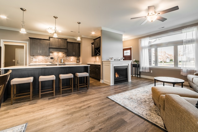 living room with light hardwood / wood-style floors, ornamental molding, sink, and ceiling fan