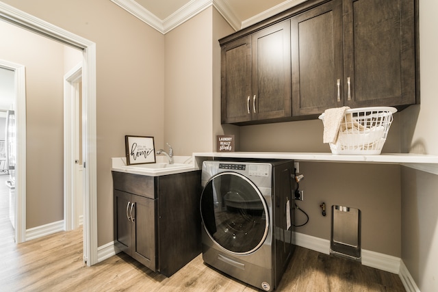 clothes washing area featuring sink, light hardwood / wood-style floors, cabinets, and washer / clothes dryer