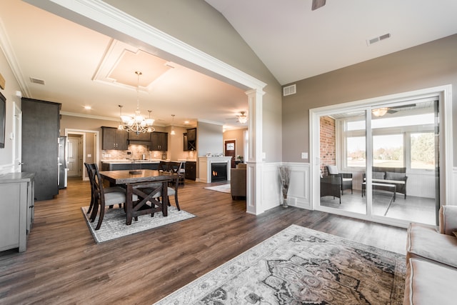 dining area with ornamental molding, lofted ceiling, dark hardwood / wood-style floors, and ceiling fan with notable chandelier