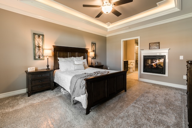 bedroom featuring light carpet, a multi sided fireplace, a raised ceiling, ensuite bathroom, and ceiling fan