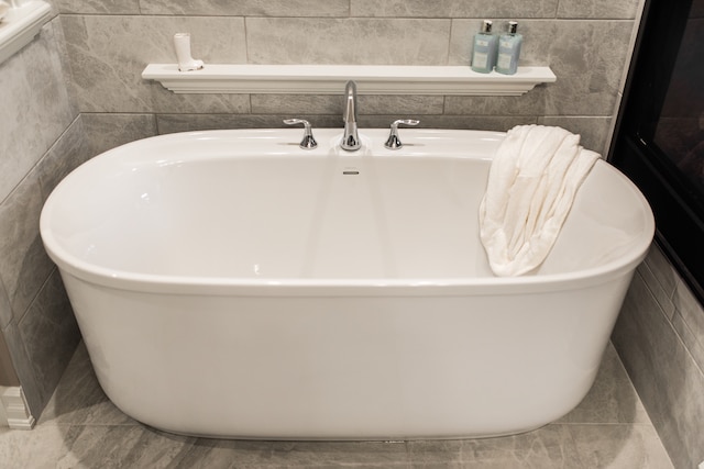 bathroom with tile walls, tile patterned floors, and a bathing tub