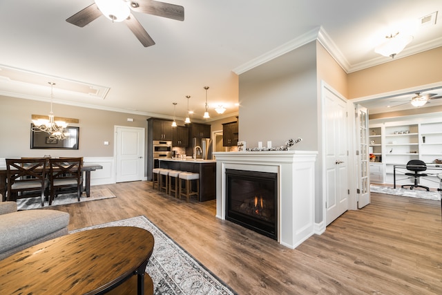 living room featuring ceiling fan, hardwood / wood-style flooring, ornamental molding, built in features, and sink