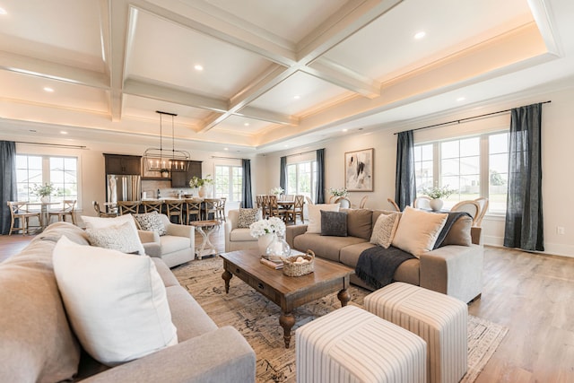 living room with beam ceiling, light wood-type flooring, coffered ceiling, crown molding, and a chandelier