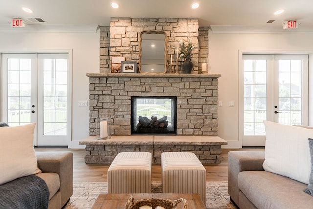 living room featuring a stone fireplace, french doors, hardwood / wood-style flooring, and crown molding