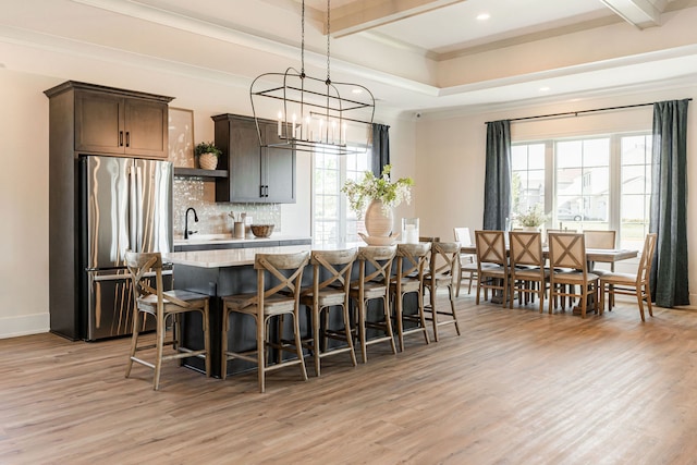 kitchen featuring light wood-type flooring, backsplash, dark brown cabinets, a center island, and stainless steel fridge