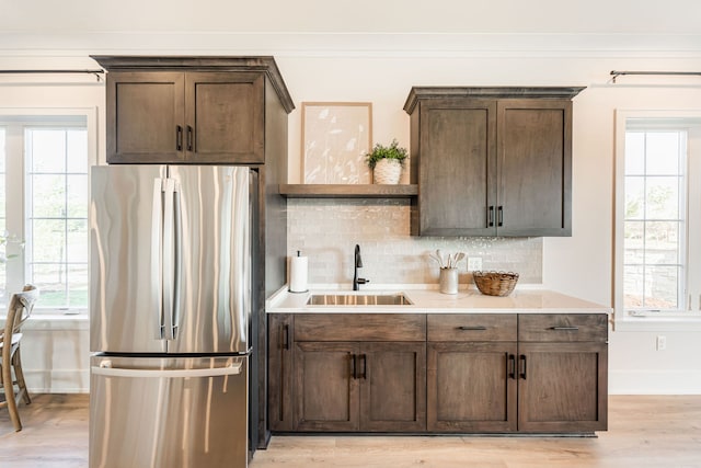 kitchen with sink, stainless steel fridge, dark brown cabinetry, and light wood-type flooring