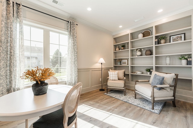 living area with light hardwood / wood-style flooring and crown molding