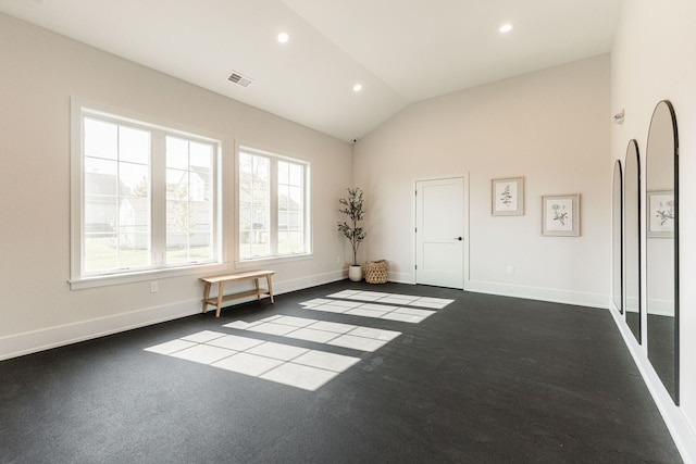 unfurnished room featuring vaulted ceiling and dark carpet