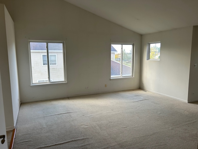 spare room featuring vaulted ceiling and light carpet