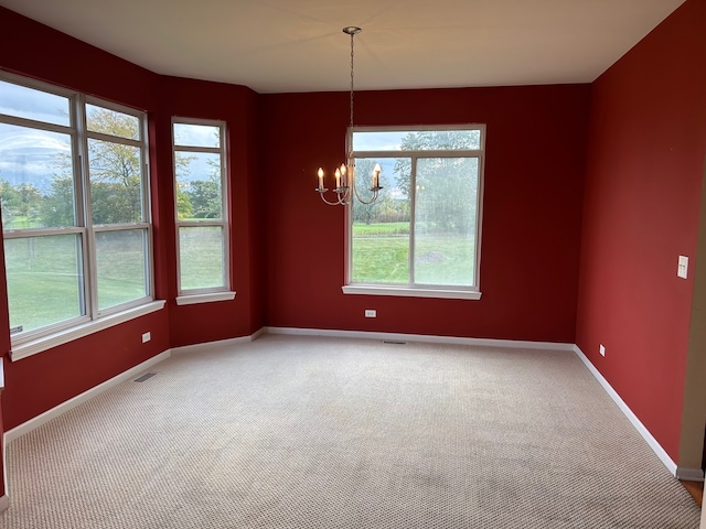 spare room featuring carpet, plenty of natural light, and a notable chandelier