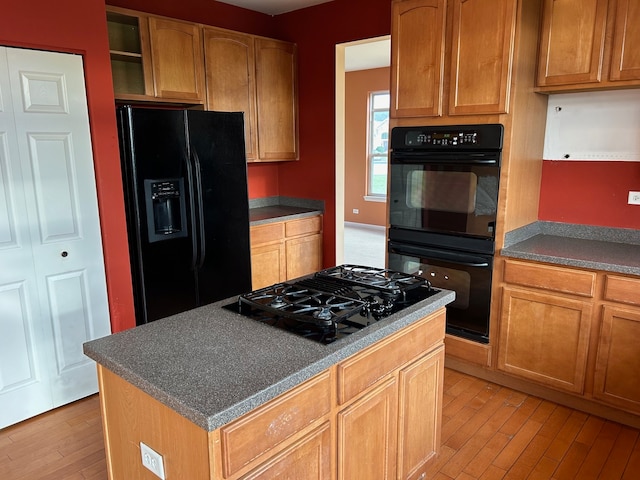 kitchen with a kitchen island, light wood-type flooring, and black appliances