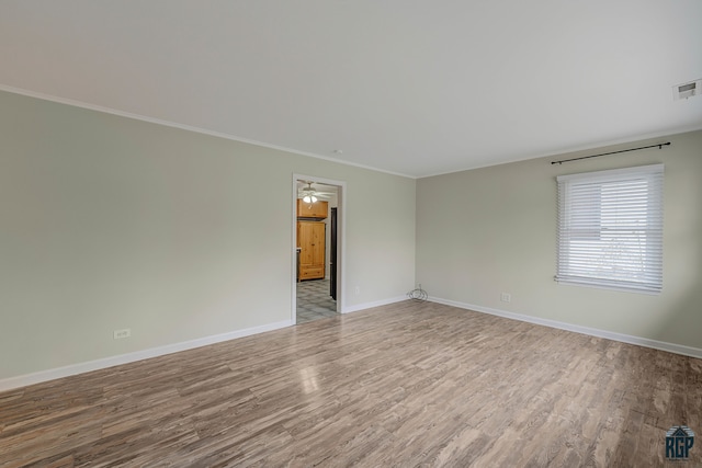 empty room featuring ornamental molding, light wood-type flooring, and ceiling fan