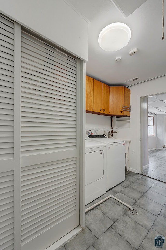 washroom featuring washer and clothes dryer, cabinets, and light tile patterned flooring