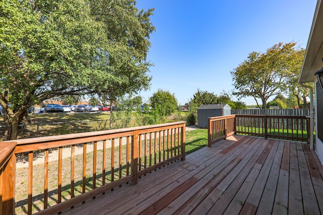 wooden terrace featuring a storage shed and a lawn