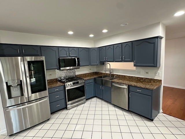 kitchen featuring appliances with stainless steel finishes, sink, backsplash, blue cabinets, and light hardwood / wood-style floors