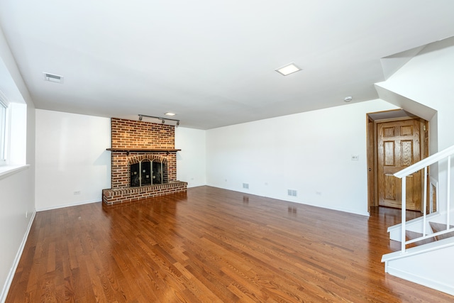 unfurnished living room featuring a brick fireplace and hardwood / wood-style flooring