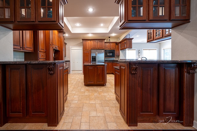 kitchen featuring a center island, stainless steel fridge, kitchen peninsula, black oven, and a tray ceiling