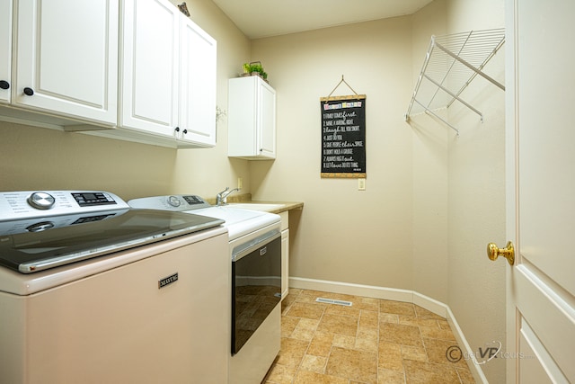 clothes washing area with cabinets, sink, and independent washer and dryer