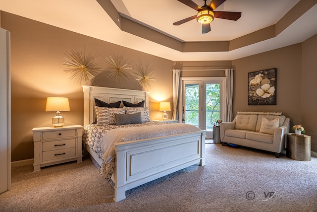 carpeted bedroom featuring ceiling fan and a tray ceiling