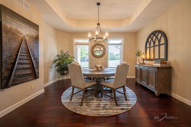 dining area featuring an inviting chandelier, a raised ceiling, and dark hardwood / wood-style flooring