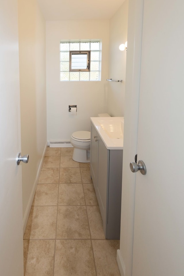 bathroom with toilet, vanity, a baseboard radiator, and tile patterned flooring