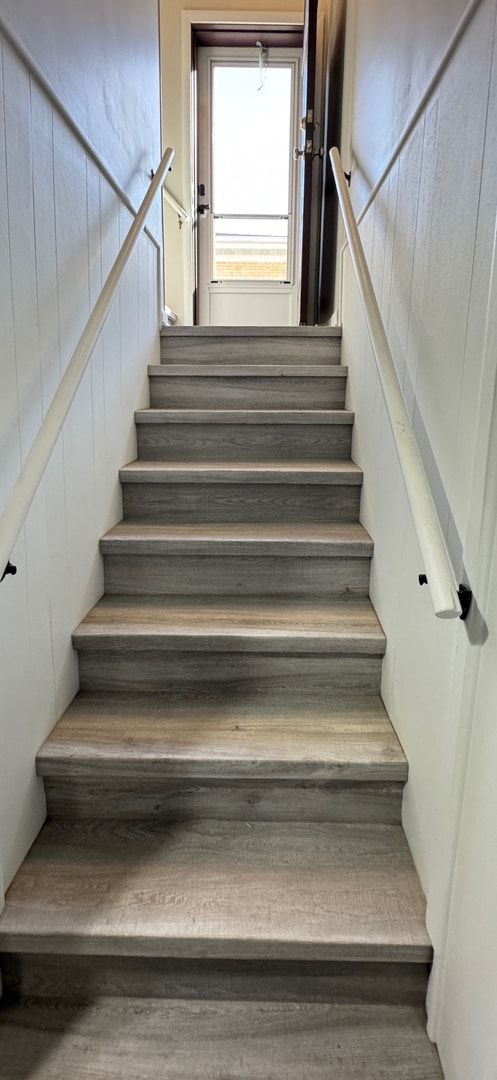 staircase with wood-type flooring and wood walls