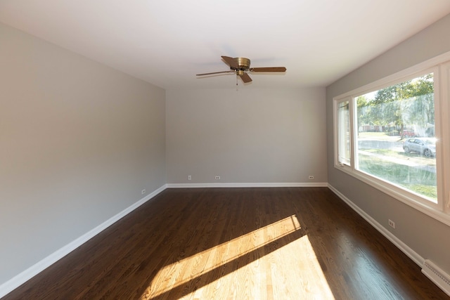 empty room with ceiling fan, a baseboard radiator, and dark hardwood / wood-style flooring