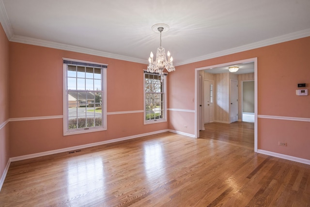 spare room featuring hardwood / wood-style floors, crown molding, and a notable chandelier