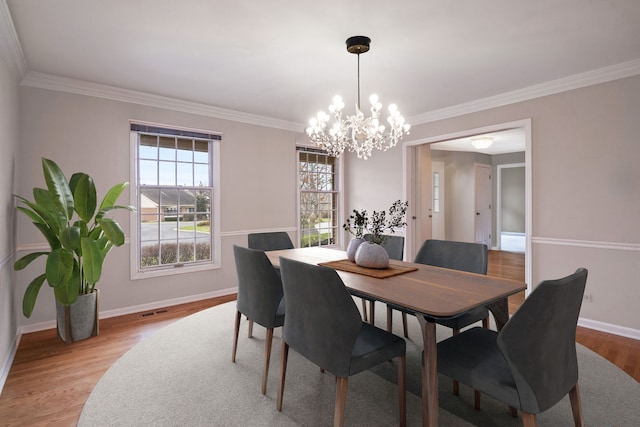 dining space with ornamental molding, a notable chandelier, and light hardwood / wood-style floors