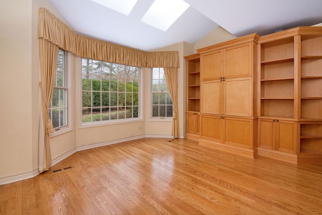 interior space featuring light hardwood / wood-style floors and lofted ceiling with skylight