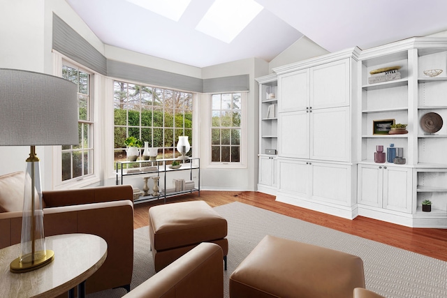 living room featuring light wood-type flooring, plenty of natural light, and vaulted ceiling with skylight