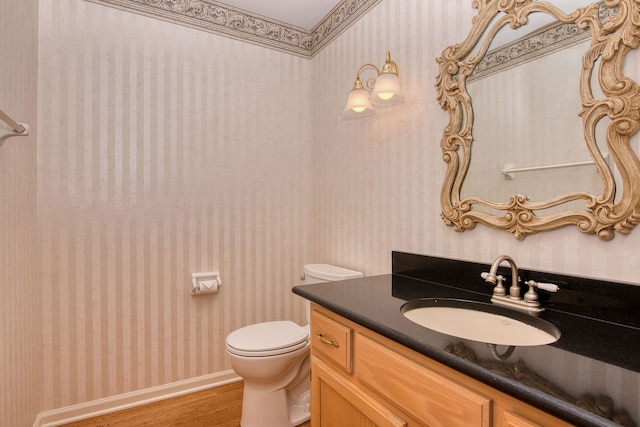 bathroom with toilet, vanity, and hardwood / wood-style flooring