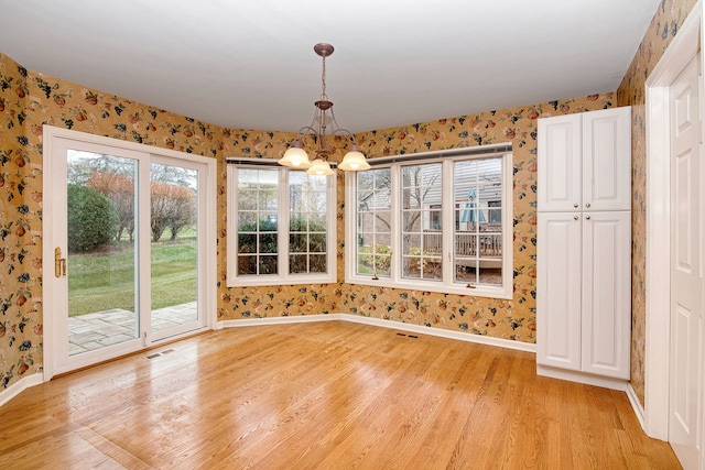 unfurnished dining area with a chandelier and light hardwood / wood-style floors