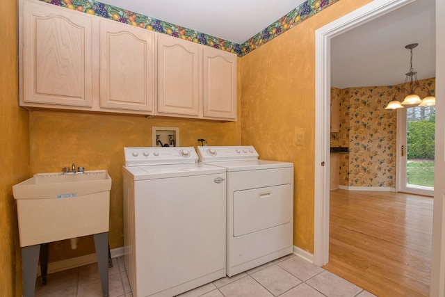 washroom with sink, independent washer and dryer, cabinets, light hardwood / wood-style floors, and an inviting chandelier