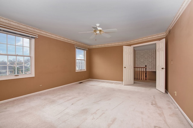 carpeted empty room with ornamental molding, ceiling fan, and a wealth of natural light