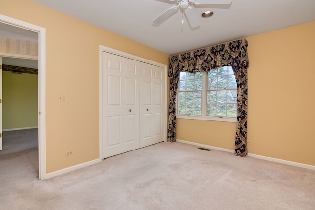 unfurnished bedroom featuring ceiling fan, a closet, and light carpet