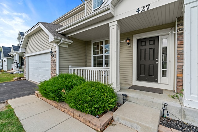 doorway to property with covered porch and a garage